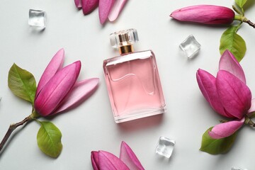Obraz na płótnie Canvas Beautiful pink magnolia flowers, bottle of perfume and ice cubes on light grey background, flat lay