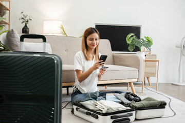 Young Asian tourist packs her suitcase, checks her belongings and passport in preparation for her weekend trip