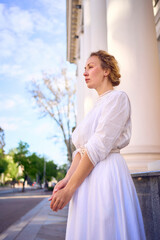 elegant middle age woman in white vintage dress near theater with antique colonnades
