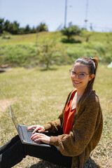 Confident lady freelancer typing information on laptop in park