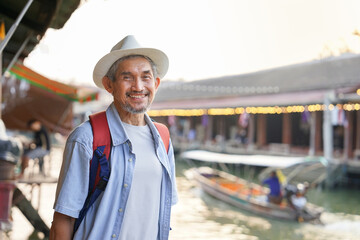 portrait healthy senior man standing and smiling at floating market in Thailand,elderly lifestyle,pensioner,retirement,travel,wellbeing