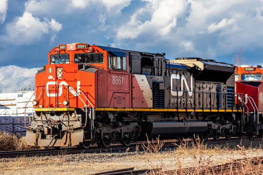 Toronto, Canada, November 13, 2023; CN Railroad engine 8861 pulling a freight train past a rtfcatory building heading West into bright sunshine