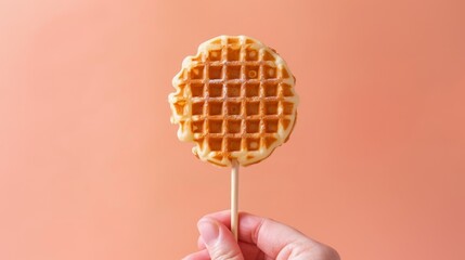 Close-up of a hand holding a crispy waffle stick on a wooden skewer, centered against an isolated background, studio lighting enhances texture