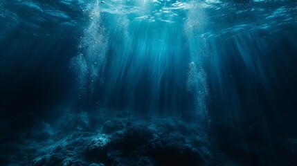 Sunbeams penetrate the deep blue ocean, creating a stunning underwater scene that captures the tranquility and mystery of the sea.