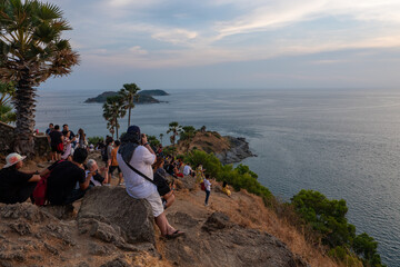 Many tourists sit and watch the sunset at Laem Promthep in Phuket province of Thailnad.