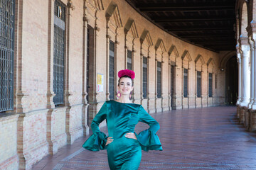 Young and beautiful woman with typical green dress with ruffles and dancing flamenco in plaza de...