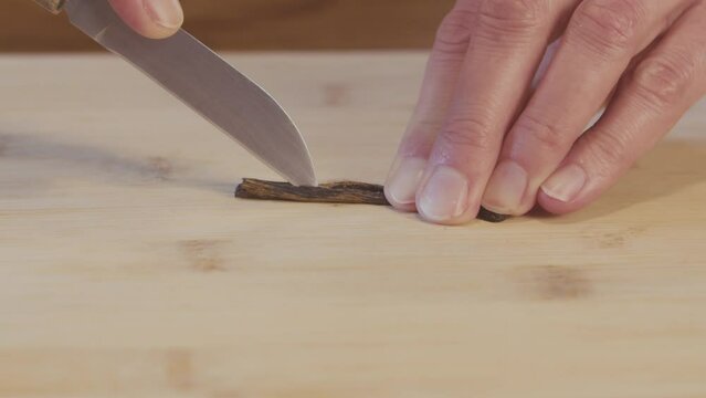 Close up of a woman chef peeling, cutting and removing the inside of vanilla stick. Kitchen, interior, studio shot. High quality 4k footage