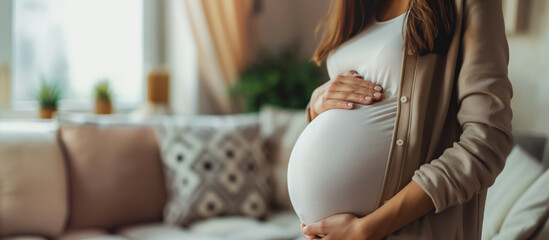 Serene pregnant woman holding her belly gently, standing in a cozy home setting.