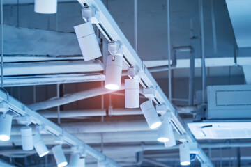 Directional LED lights on rails under the ceiling in a modern warehouse, shopping center building, office or other commercial real estate object.