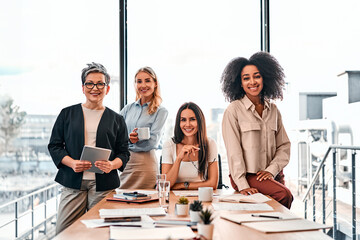 Group of businesspeople.Leadership concept.Four diverse women in a modern office looking at the camera and smiling. Copy space.