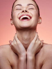 Portrait of a joyful woman with hands on face and neck smiling at camera in a relaxed pose