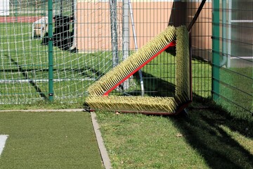 a large triangular broom attached to the fence for maintenance of the football field