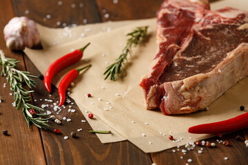 Raw piece of meat steak with rosemary on wooden table