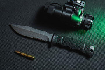 Tactical knife with a fixed blade, gt14 night vision device and 5.56x45mm cartridge.