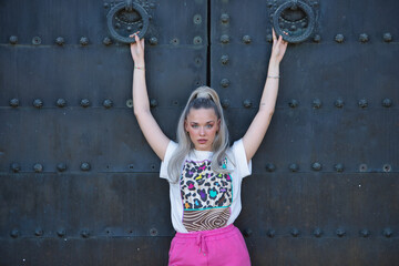 Young, pretty, blonde woman with blue eyes, printed T-shirt and pink skirt, looking at the camera,...