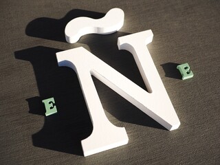 White wooden ñ letter on a grey background. Eñe Spanish language symbol
