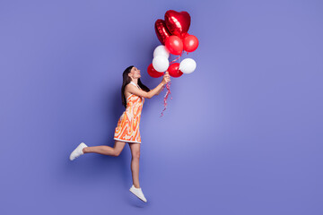 Full length profile portrait of nice lady hold balloons jump empty space wear dress isolated on...