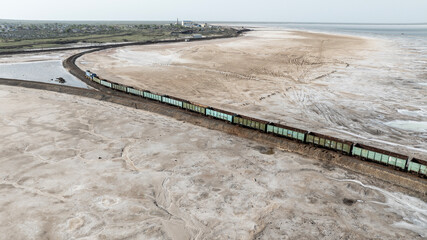 a train travels across a salt lake to transport salt in the area of Lake Baskunchak on a spring day