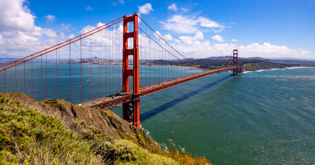 San Francisco Bay panorama with red colored Golden Gate Bridge from view point ”Battery Spencer“ on a clear sunny spring afternoon. Iconic infrastructure monument and world famous tourist attraction. - obrazy, fototapety, plakaty