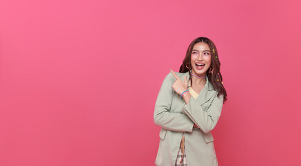 Happy young Asian teen woman standing with her pointing finger isolated on pink background with...