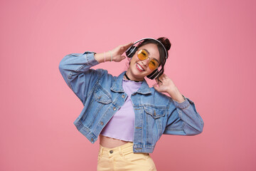 Happy young asian woman listening music with headphone dancing isolated on pink background. People lifestyle relax concept.