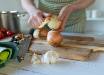 Person peeling an onion on a cutting board in the kitchen