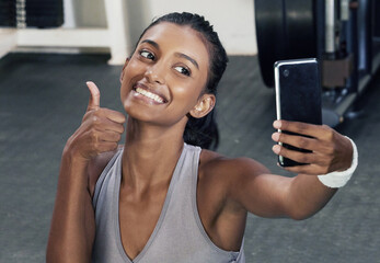 Woman, thumbs up and selfie on phone in gym for social media post or wellness blog in training....