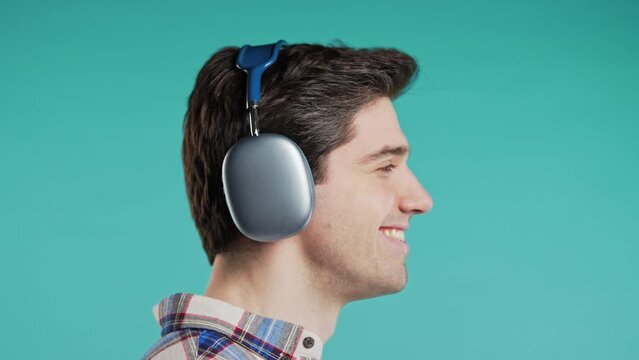 Positive handsome man listening music, enjoying dance with modern headphones