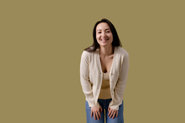Cheerful brunette asian woman in casual clothes looking at camera isolated on green 