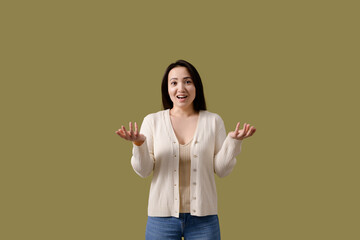 Cheerful young asian woman in cardigan looking at camera isolated on green 