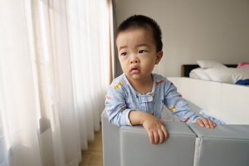 Sleepy Asian baby boy looking at window after waking up
