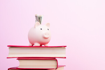 Piggy bank in glasses and books on pink background. open book. Tuition payment. Brainwork. Back to...