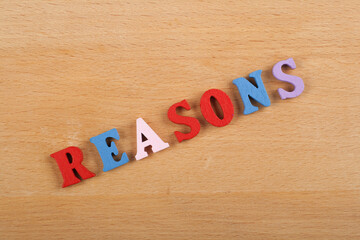 REASONS word on wooden background composed from colorful abc alphabet block wooden letters, copy...