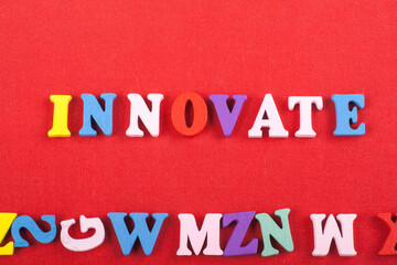 INNOVATE word on red background composed from colorful abc alphabet block wooden letters, copy space for ad text. Learning english concept.