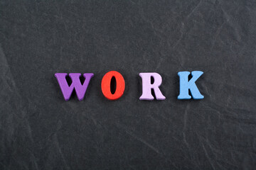 WORK word on black board background composed from colorful abc alphabet block wooden letters, copy...