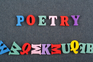 POETRY word on black board background composed from colorful abc alphabet block wooden letters, copy space for ad text. Learning english concept.