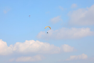 Two people practicing extreme sports with paragliders flying high in the sky, also a symbol of carefreeness - obrazy, fototapety, plakaty