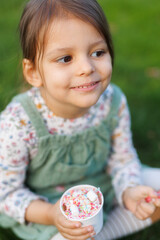 Little girl with emotions eats ice cream on the street in the park.