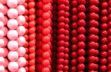 background of colorful necklaces made of red and pink pearls in the shop