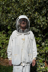 Portrait of beekeeper looking at camera smiling and posing, futuristic protective suit with...