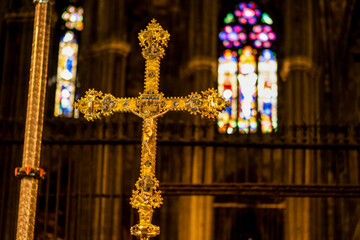 Cruz de oro con las vidrieras de la iglesia de fondo, luz solar en un lugar sagrado