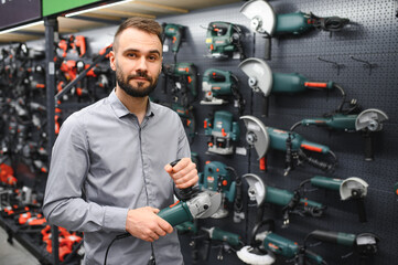 a buyer in a hardware store walks between with a power tool