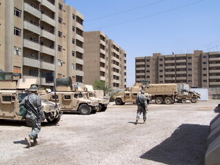 Military vehicles parked in a courtyard surrounded by apartment buildings at FOB Loyalty during Operation Iraqi Freedom in Baghdad, Iraq