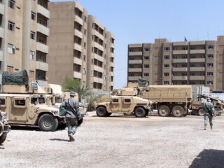 Military vehicles parked in a courtyard surrounded by apartment buildings at FOB Loyalty during...