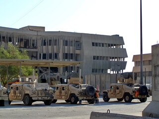 Military vehicles parked in front of a bombed out building at FOB Loyalty during Operation Iraqi Freedom in Baghdad, Iraq