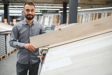 A male salesman-consultant in a hardware store sells laminate