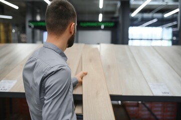 A young man chooses laminate flooring in the hardware store