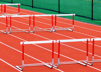 Hurdles set up on a red track for an outdoor race