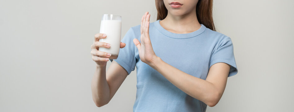 Allergy asian young woman, girl hand in deny, no or push out to avoid for drink milk at home, unhappy and bad stomach ache. Lactose intolerance and dairy food, health problem, belly suffer concept.
