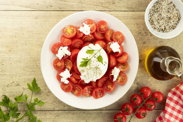 Salad with tomatoes and burrata cheese with  olive oil on wooden background.